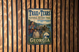 A vintage metal sign for the Trail of Tears National Historic Trail in Georgia, featuring an illustration of a group of people on a wagon train crossing a river.