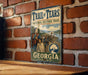 A vintage metal sign for the Trail of Tears National Historic Trail in Georgia, featuring an illustration of a group of people on a dirt road.