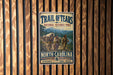 A vintage-style metal sign for the Trail of Tears National Historic Trail, featuring a historical illustration of a group of people crossing a river.