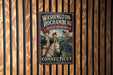 A vintage-style metal sign for the "Washington-Rochambeau Revolutionary Route" in Connecticut, featuring a man in military uniform and a horse, mounted on a wooden wall.