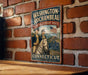 A vintage-style metal sign with the text "Washington-Rochambeau Revolutionary Route" and an illustration of two men on horseback, mounted on a brick wall.