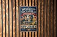 A vintage-style metal sign for Washington-Rochambeau Revolutionary Route, featuring two men in historical uniforms and an American flag, mounted on a wooden wall.