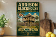 A vintage-style sign for Addison Blockhouse Historic State Park in Florida, featuring a wooden cabin surrounded by palm trees and a flag.