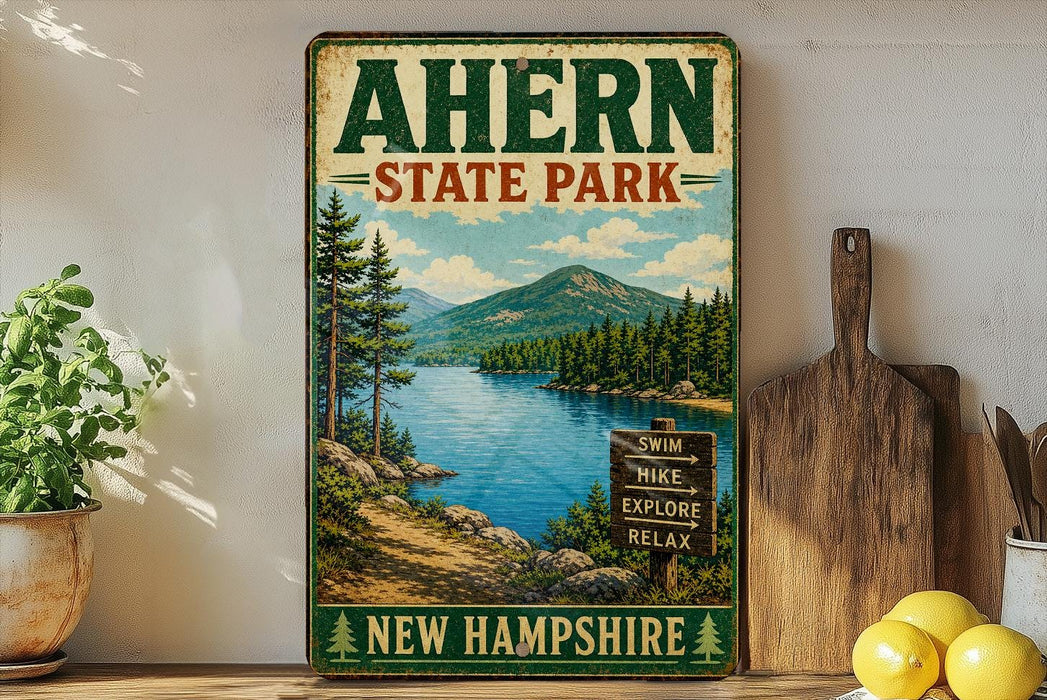 a vintage-style sign for Ahern State Park in New Hampshire, with a scenic landscape depicting a lake surrounded by pine trees and mountains.