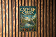 A vintage metal sign for Catfish Creek Preserve in Florida, featuring a large bird and a serene landscape.