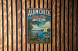A vintage-style metal sign for Alum Creek State Park in Ohio, featuring a scenic image of a lake with a sailboat and a forested shoreline.