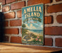 A vintage metal sign for Amelia Island, Florida, featuring a beach scene with a turtle and palm trees, mounted on a brick wall.