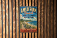 A vintage metal sign for Amsterdam Beach State Park in New York, featuring a beach scene and a lighthouse, is displayed on a wooden wall.
