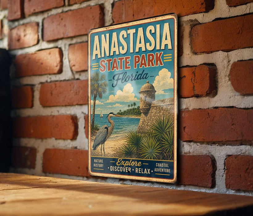 A vintage-style metal sign for Anastasia State Park in Florida, featuring a beach scene with palm trees and a lighthouse, mounted on a brick wall.