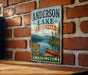 A vintage-style metal sign for Anderson Lake State Park in Washington, featuring a scenic image of a lake, mountains, and a canoe.