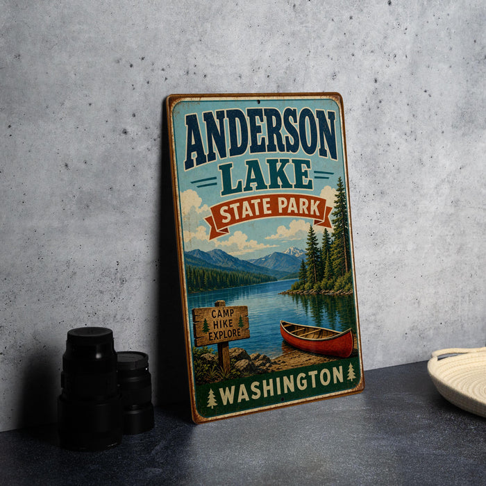 A vintage-style sign for Anderson Lake State Park in Washington, featuring a scenic image of a lake, mountains, and a red canoe.