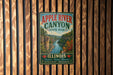 A vintage-style metal sign for Apple River Canyon State Park in Illinois, featuring a scenic illustration of the canyon and its surroundings.