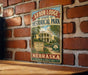 A vintage-style sign for Arbor Lodge State Historical Park in Nebraska, featuring a brick wall and a wooden table in the background.