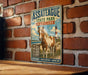 A vintage metal sign for Assateague State Park in Maryland, featuring a horse and a lighthouse, is displayed on a brick wall.