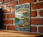A vintage metal sign for Badger Creek State Recreation Area in Iowa, featuring a scenic illustration of a lake, canoe, and trees.