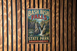 A vintage-style metal sign for Bash Bish Falls State Park in Massachusetts, featuring a waterfall and lush greenery.