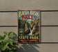 A vintage-style metal sign for Bash Bish Falls State Park in Massachusetts, featuring a waterfall and lush greenery.