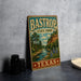 A vintage-style metal sign for Bastrop State Park in Texas, featuring a scenic illustration of a river and lush greenery.
