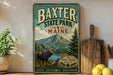 A vintage-style metal sign for Baxter State Park in Maine, featuring a moose and a mountain landscape.