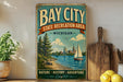 A vintage-style metal sign for Bay City State Recreation Area in Michigan, featuring a scenic illustration of a lake, pine trees, and a sailboat.