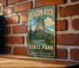 A vintage-style metal sign for Beacon Rock State Park in Washington, featuring a scenic illustration of the park's landscape.