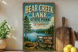 A vintage-style metal sign for Bear Creek Lake State Park in Virginia, featuring a scenic landscape with a lake, mountains, and a picnic table.