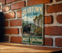 A vintage-style metal sign for Beartown State Park in West Virginia, featuring a black bear in a natural setting.