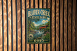 A vintage metal sign for Beaver Creek State Park in Ohio, featuring a scenic image of the park's waterfall and surrounding landscape.