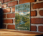 A vintage metal sign for Beaver Creek Valley State Park in Minnesota is displayed on a brick wall.