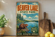 A vintage-style sign for Beaver Lake State Park, featuring a beaver in a natural setting with a lake and trees.