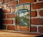 A vintage-style metal sign for Beaver Bend State Park in Oklahoma, featuring a scenic illustration of a beaver in a river surrounded by trees and mountains.