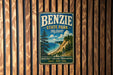 A vintage metal sign for Benzie State Park in Michigan, featuring a scenic landscape with a beach, mountains, and pine trees.