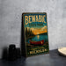 A vintage-style metal sign for Bewabic State Park, featuring a canoe and a scenic landscape, is displayed on a gray countertop next to some black camera lenses.