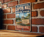 A vintage-style metal sign for the historic capitol mall in Tennessee, featuring a cityscape and the text "BICENTENNIAL CAPITOL MALL STATE PARK TENNESSEE".
