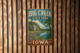 A vintage-style metal sign for Big Creek State Park in Iowa, featuring a scenic landscape with a river, trees, and flowers.