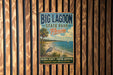 A vintage-style metal sign for Big Lagoon State Park in Florida, featuring a beach scene with palm trees and a crane, is displayed on a wooden fence.