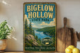 A vintage-style sign for Bigelow Hollow State Park, featuring a scenic landscape with pine trees, a river, and mountains.