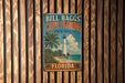 A vintage metal sign for Bill Bagg's Cape Florida State Park, featuring a lighthouse and palm trees, is displayed on a wooden wall.
