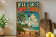 A vintage-style sign for Bill Bagg's Cape Florida State Park, featuring a lighthouse, palm trees, and a beach scene.