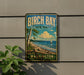 A vintage-style sign for Birch Bay State Park in Washington, featuring a scenic image of a lake, trees, and a sailboat.