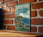 A vintage-style metal sign for Birch Point State Park in Maine, featuring a scenic landscape with a rocky coastline, pine trees, and a blue sky with clouds.