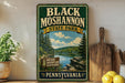 A vintage-style sign for Black Moshannon State Park in Pennsylvania, featuring a scenic landscape with a lake and pine trees.