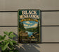 A vintage-style metal sign for Black Moshannon State Park in Pennsylvania, featuring a scenic landscape with pine trees, a lake, and mountains.