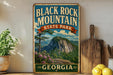 A vintage-style sign for Black Rock Mountain State Park in Georgia, featuring a scenic mountain landscape with pine trees and a rocky peak.