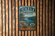 A vintage metal sign for Black Rock State Park in Connecticut, featuring a scenic landscape with a lake, mountains, and a sailboat.