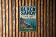 A vintage metal sign for Black Sandy State Park in Montana, featuring a scenic landscape with a lake, mountains, and pine trees.