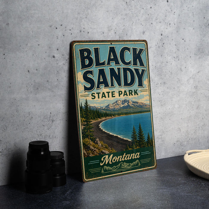 A vintage-style sign for Black Sandy State Park in Montana, featuring a scenic landscape with a lake, mountains, and pine trees.