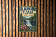 A vintage-style sign for Blackwater Falls State Park in West Virginia, featuring a waterfall surrounded by pine trees and pink flowers.