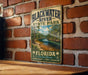 A vintage-style metal sign for Blackwater River State Park in Florida, featuring a scenic image of the river surrounded by lush greenery.