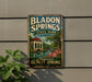 A vintage-style metal sign for Bladen Springs State Park in Alabama, featuring a scenic illustration of the park's landscape and architecture.